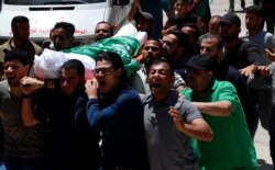 Dolientes cantan consignas islámicas mientras llevan el cuerpo de Awad Abu Selmiya, durante un funeral de trece militantes de Hamas frente a una mezquita en la ciudad de Gaza, el jueves 13 de mayo de 2021.