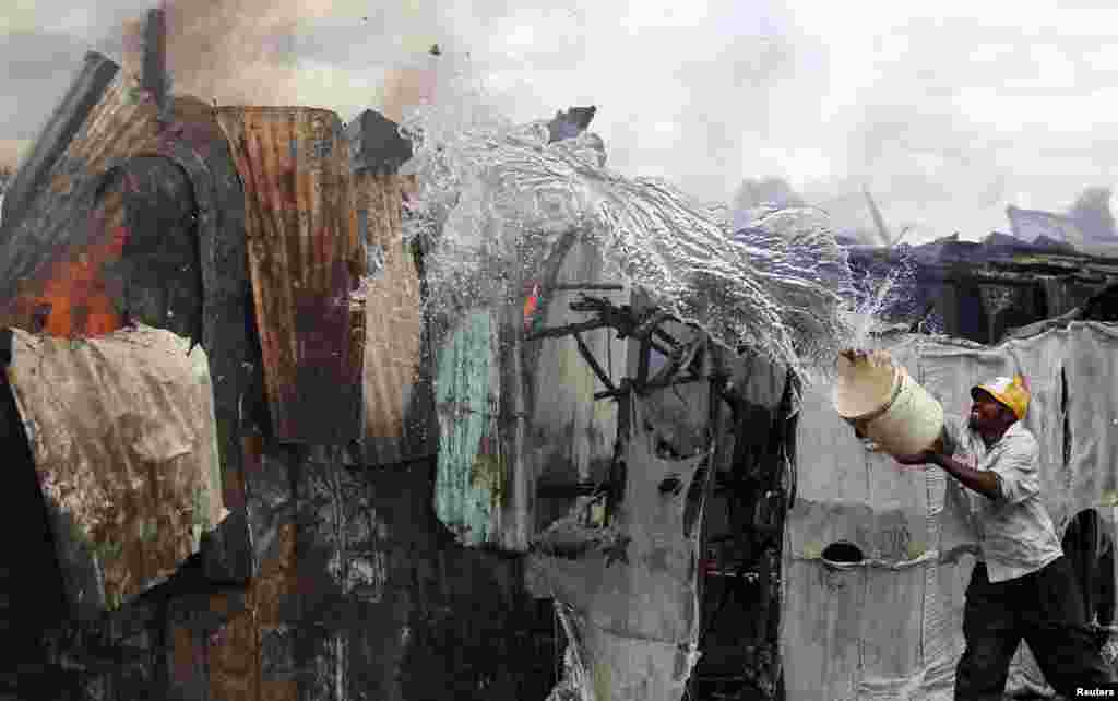 A trader attempts to extinguish fire with a bucket of water at the City Stadium open air market in Kenya&#39;s capital Nairobi.