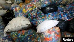 FILE - Bags filled with caps are pictured at the Association Bouchon d'Amour, which collects and recycles plastic caps in Martignas-Sur-Jalles, near Bordeaux, France, Nov. 23, 2018.