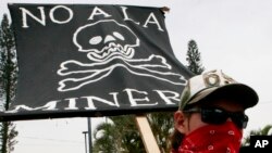 FILE - A protester holds a sign that reads in Spanish "No to mining" at a protest against Canada's gold and silver mining operations in northern El Salvador, outside Canada's Consulate office in San Salvador, May 21, 2007.