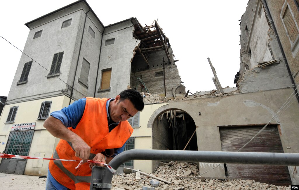 A volunteer ropes off the area surrounding a collapsed building in Finale Emilia, northern Italy after a quake hit northern Italy May 20, 2012. (AP Photo/Marco Vasini)