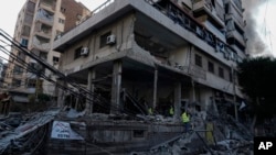 Emergency workers inspect a building that was hit in an Israeli airstrike in Dahiyeh, Beirut, Lebanon, Oct. 6, 2024. 