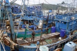 FILE - Police officers stand on a fishing boat during a police inspection at the pier of Songkhla, south Thailand, Dec. 23, 2015.