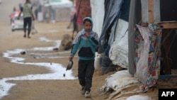 Palestinsko dijete bježi da se skloni od kiše u kamp, 20. decembra 2024. godine. (Foto: Eyad BABA/AFP