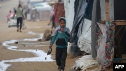 A Palestinian child runs to shelter from the rain at the Nuseirat refugee camp in the Gaza Strip on Dec. 20, 2024.