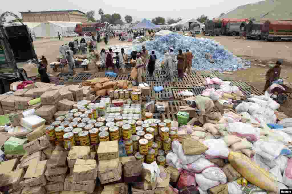 Des travailleurs remplissent des brouettes de l&#39;aide pour les déplacés à l&#39;intérieur d&#39;un centre de distribution alimentaire dans un stade à Bannu, dans le nord-Pakistan, le 25 Juillet 2014. 