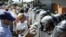Opposition supporters hold packages of corn flour in front of riot police during a rally against Venezuelan President Nicolas Maduro's government in San Cristobal, Jan. 23, 2017.