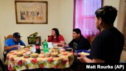 Keldy Mabel Gonzales Brebe, 37, sits for lunch with her sons, from left, Mino Zuniga Gonzales, 19, Erick Zuniga Gonzales, 17, and Alex Zuniga Gonzales, 21, in the Kensington section of Philadelphia, Sunday, May 16, 2021. (AP Photo/Matt Rourke)