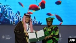 FILE—Director-General of the WTO Ngozi Okonjo-Iweala and Saudi Minister of Commerce and Investment Majid al-Qasabi pose for a picture with signed documents during a session on fisheries subsidies at the WTO Ministerial Conference in Abu Dhabi, February 26, 2024.