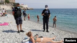 Manm polis minmisipal la an Frans avèk kachne nan figi yo, ki t ap pale ak yon dam sou Plaj "Promenade des Anglais" nan vil Nice, nan dat 22 me 2020 an, apre otorite yo te pran desizyon pou yo relouvri plaj yo. (Foto: REUTERS/Eric Gaillard). 