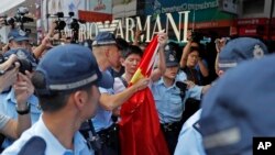 A pro-China supporter, holding a Chinese national flag at center, is escorted by police officers in a shopping mall in Hong Kong, Sept. 18, 2019.