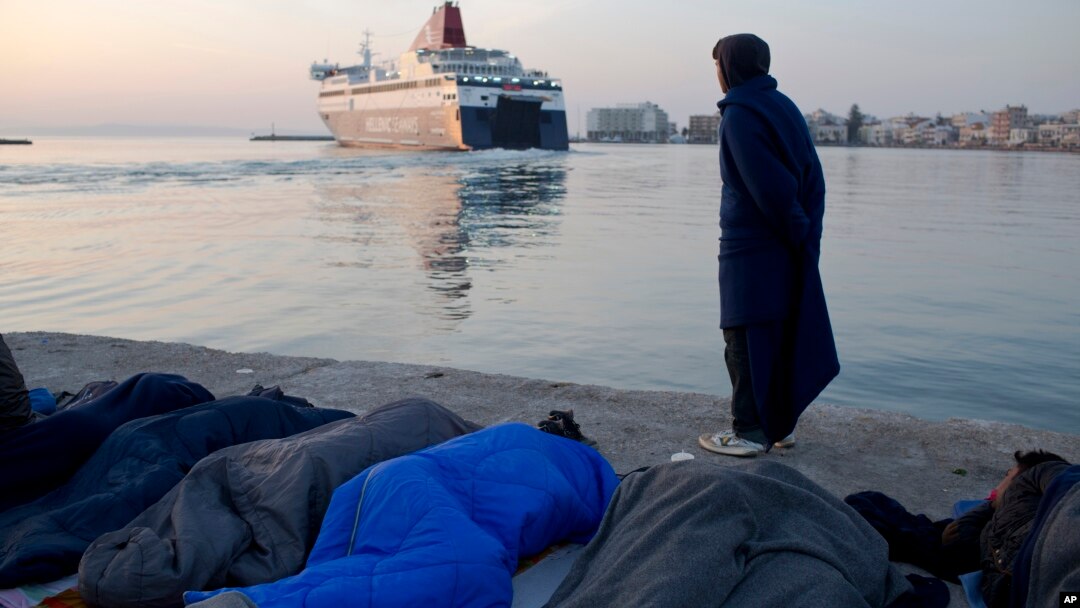 Izbeglica iz Pakistana pored migranata koji spavaju posmatra kako brod odlazi iz luke sa grčkog ostrva Hios, 6. april 2016.