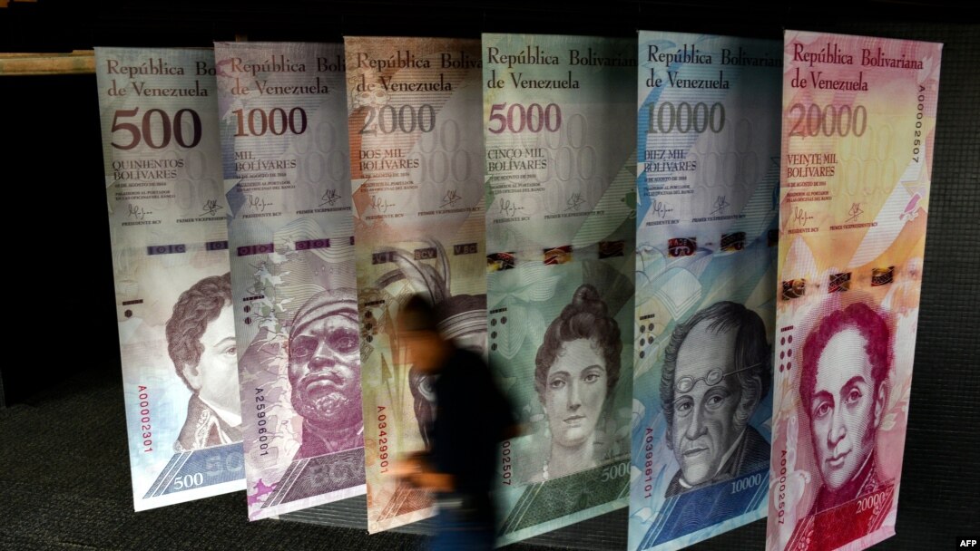 A man walks past banners showing banners depicting Venezuela's currency, the Bolivar, at the Central Bank of Venezuela in Caracas on Jan. 31, 2018.