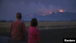 Local residents look at smoke and fire over a hill during wildfires near the town of Medford, Oregon, Sept. 9, 2020. 