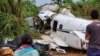 Sejumlah orang memperhatikan pesawat yang jatuh di Barcelos, negara bagian Amazonas, Brazil, Sabtu, 16 September 2023. Empat belas orang dinyatakan tewas dalam kecelakaan tersebut. (Foto: Wellington Melo/Reuters)