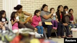 Migrants sit at the Sacred Heart Catholic Church temporary migrant shelter in McAllen, Texas, June 27, 2014.