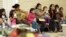 FILE - Migrants sit at the Sacred Heart Catholic Church temporary migrant shelter in McAllen, Texas, June 27, 2014.