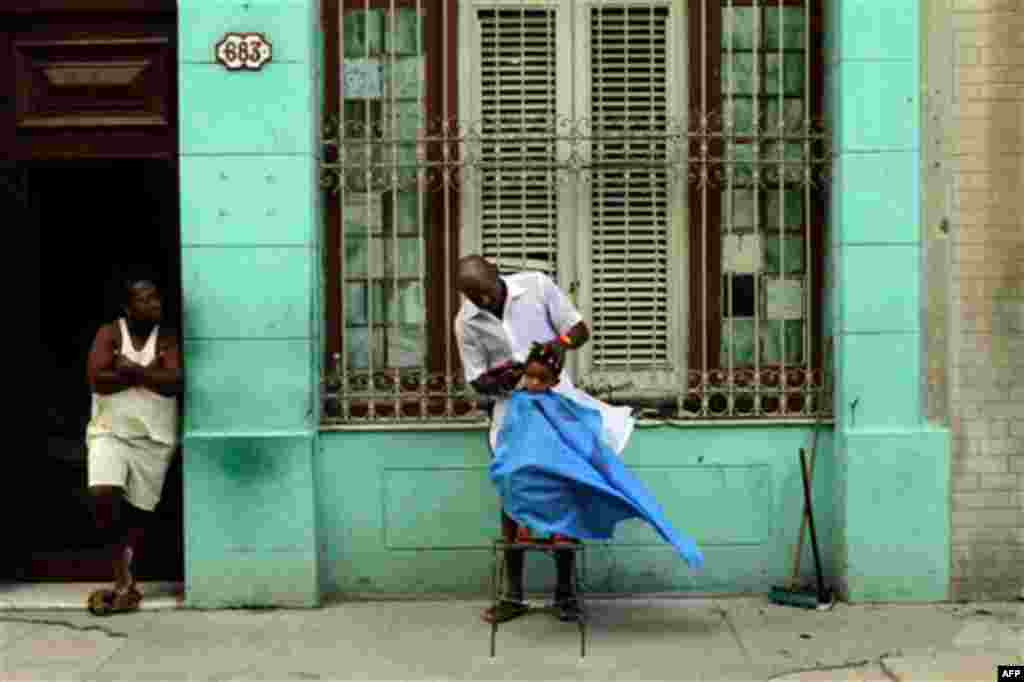 Barber Orlando Gonzalez cuts the hair of young client Maikol as Gonzalez' sister Cilia looks on along a sidewalk in Havana, Cuba, Wednesday Oct. 6, 2010. (AP Photo/Franklin Reyes)