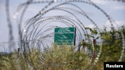 FILE - A warning sign behind a wire barricade erected by Russian and Ossetian troops along Georgia's de-facto border with its breakaway region of South Ossetia in the village of Khurvaleti, Georgia, July 14, 2015. 