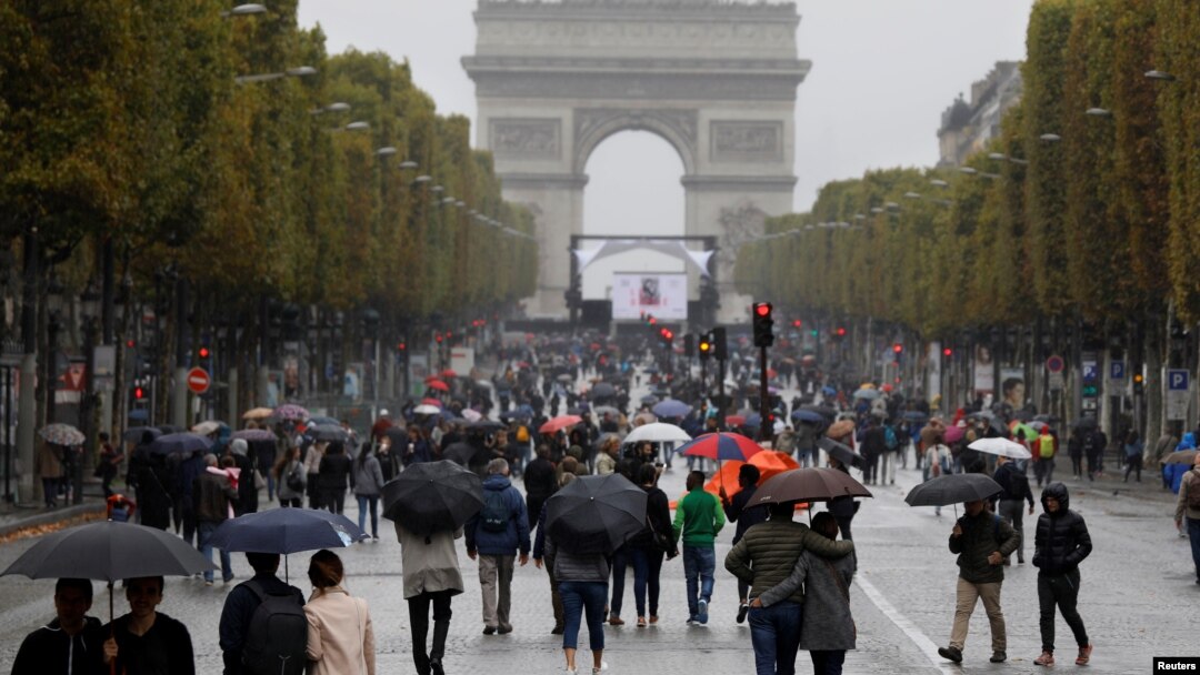 FILE - Pedestrians walk on the Champs Elysees avenue during the Car Free Day in Paris, Oct. 1, 2017. 