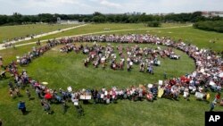 Protesters encircle a group standing to form letters that spell "Impeach Trump," during a rally to protest President Donald Trump and his policies, on the National Mall in Washington, June 3, 2017.