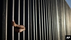 FILE - In this June 13, 2013, photo, hands from Daniel Zambrano of Tijuana, Mexico, hold on to the bars that make up the border wall separating the U.S. and Mexico as the border meets the Pacific Ocean in San Diego.