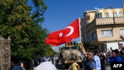 Seorang pria melambaikan bendera Turki saat kombatan oposisi Suriah yang didukung Turki menuju Tal Abyad dari gerbang Turki menuju Suriah di Akcakale di Provinsi Sanliurfa, 10 Oktober 2019. 