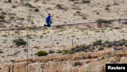 Daredevil Nik Wallenda gives a thumbs-up sign as he nears the end, after walking on a two-inch (5-cm) diameter steel cable rigged 1,400 feet (426.7 metres) across more than a quarter-mile deep remote section of the Grand Canyon near Little Colorado River