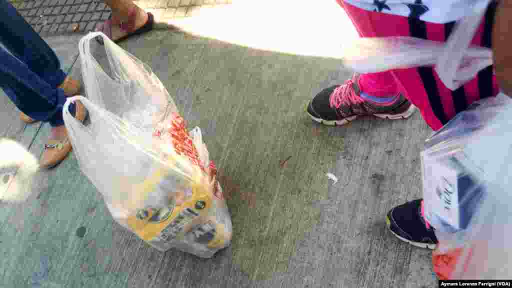 Luego de horas de cola los venezolanos vigilan las bolsas con las compras de los productos escasos.
