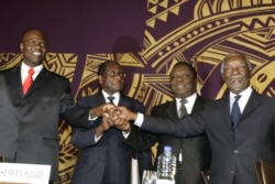 FILE - Officials join hands at the signing of power-sharing deal in Harare, Zimbabwe, Sept, 15, 2008. From left: Arthur Mutmbara, deputy prime minister; Robert Mugabe, president; Morgan Tsvangirai, prime minister; and Thabo Mbeki, South Africa's president.