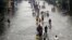 People walk on a flooded street in suburban Pasig City, east of Manila, Philippines, August 9, 2012.