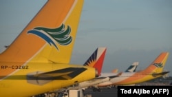 Pesawat Cebu Pacific (pertama, kiri), pesawat Philippines Airlines (kedua dari kiri) dan Cathay Pacific parkir di tarmac Bandara Internasional Manila, 2 November 2015. (Foto: Ted Aljibe/AFP Photo)