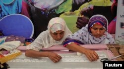 Women work on embroidery at a stall during a visit by U.S. Agency for International Development (USAID) Administrator Rajiv Shah (unseen) in an occasion to highlight the work of female micro entrepreneurs in Karachi.