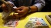 An employee counts British pounds and Euro notes at a currency exchange office.