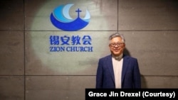 File photo: Pastor Ezra Jin Mingri stands before the Zion Church logo in Beijing.