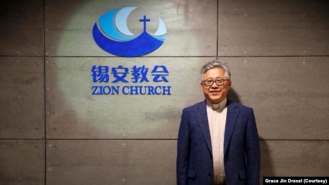 File photo: Pastor Ezra Jin Mingri stands before the Zion Church logo in Beijing.
