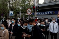 People wearing face masks to guard against COVID-19 leave work after office hours in the Central Business District in Beijing, China, April 17, 2020.