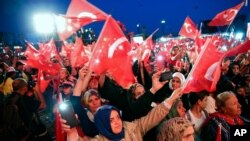 People wave Turkish flags as they listen to Turkey's President Recep Tayyip Erdogan during a rally to honor the victims of the July 15, 2016 failed coup attempt, part of the ceremonies for the three-year anniversary, in Istanbul, July 15, 2019.