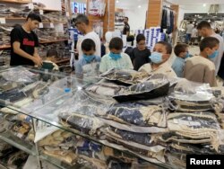 Children wear protective face masks as they look at clothes in a shop ahead of the Eid al-Adha celebrations amid the coronavirus disease (COVID-19) pandemic, in Misrata, Libya, July 28, 2020.