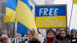 Protesters hold signs and wave Ukrainian flags during a demonstration in support of Ukraine outside of an EU foreign ministers meeting at the European Council building in Brussels on Jan. 23, 2023.