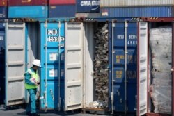FILE - A Malaysian official inspects a container filled with plastic waste shipment prior to sending it to the Westport in Port Klang, Malaysia, May 28, 2019.
