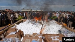 Police officers and people look on as government officials light a fire during a ceremony to dispose of confiscated drugs, in Phnom Penh August 28, 2012. Authorities burned more than one ton worth of drugs during a ceremony on Tuesday morning, reported local media. REUTERS/Samrang Pring