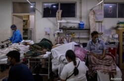 Manika Goel, sentada junto a su esposo, que sufre el COVID-19, dentro de la sala de emergencias del hospital Holy Family en Nueva Delhi, India, el 29 de abril de 2021.