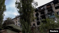 FILE - A police officer walks near a damaged residential building in the town of Avdiivka, Donetsk region, Ukraine, Oct. 17, 2023. A U.S. official said some Russian soldiers found dead in recent fighting near the town were killed by order of their own leaders. 