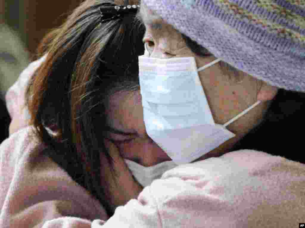 People hug each other in an evacuation center set up in a middle school gymnasium in Rikuzentakata City, Iwate Prefecture in northeastern Japan March 12, 2011. Japan confronted devastation along its northeastern coast on Saturday, with fires raging and pa