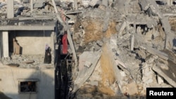 A Palestinian woman stands in a destroyed building as she inspects the site of Israeli strikes amid the ongoing conflict between Israel and Hamas in Khan Younis, Gaza, on Dec. 6, 2023.