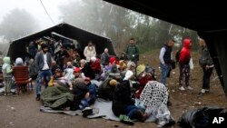 Sekelompok migran menunggu untuk menyeberang perbatasan antara Serbia dan Kroasia, sekitar 100 kilometer sebelah barat Belgrad, Serbia (18/10). (AP/Darko Vojinovic) 