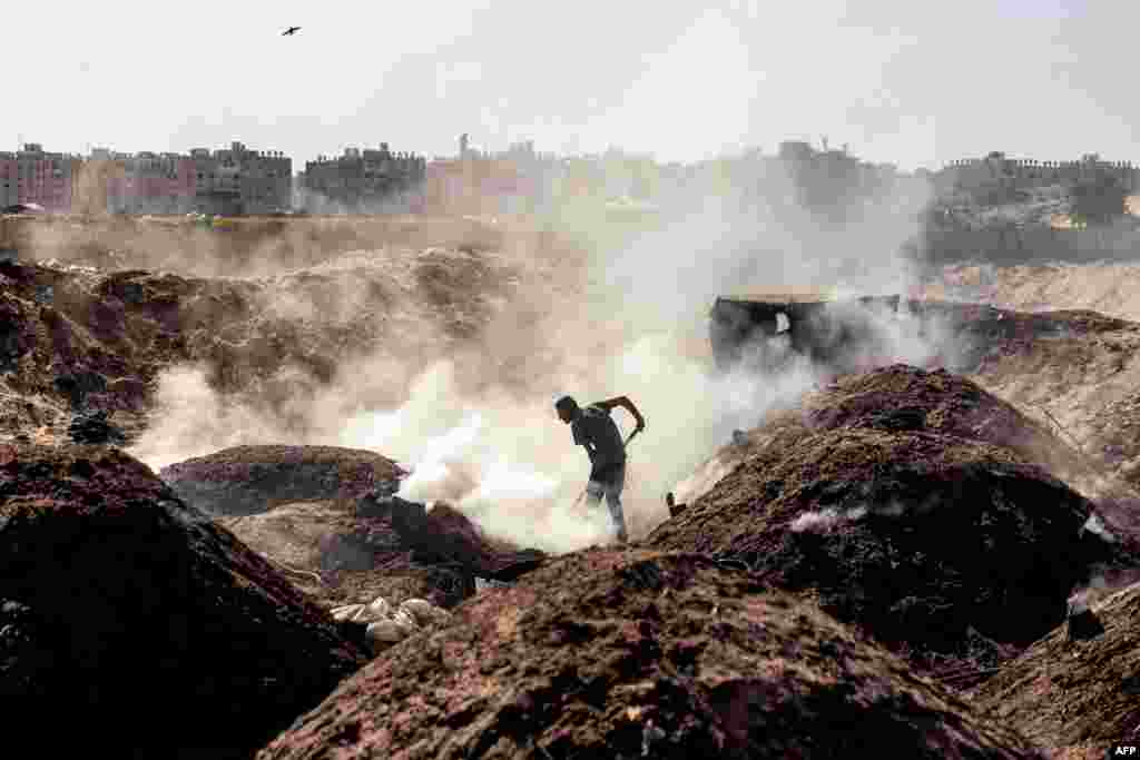 Seorang pria menyekop tanah di lokasi produksi arang di Khan Yunis di Jalur Gaza selatan, di tengah pertempuran antara Israel dan Hamas. (AFP)&nbsp;