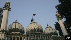 A Muslim man hoists a black flag atop a mosque in Ayodhya, about 600 km (375 miles) southeast of New Delhi, December 6, 2009. Indian Muslims on Sunday observed the 17th anniversary of the razing of the16th century Babri mosque by Hindu mob in the town of 