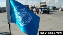 Bendera PBB di kota perbatasan Turki Kilis dengan latar belakang truk yang mengirimkan bantuan ke Suriah.